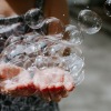 child holding bubbles in her hand as some float away