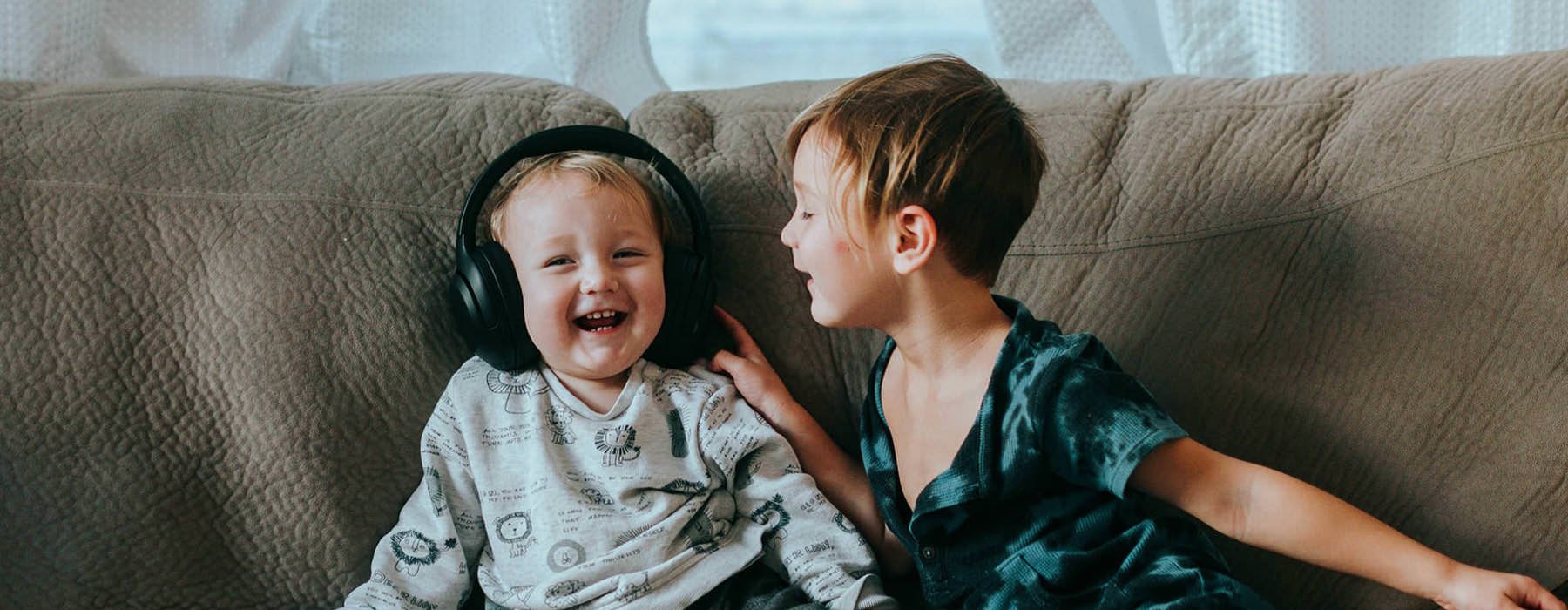 young brothers sit together on a large couch